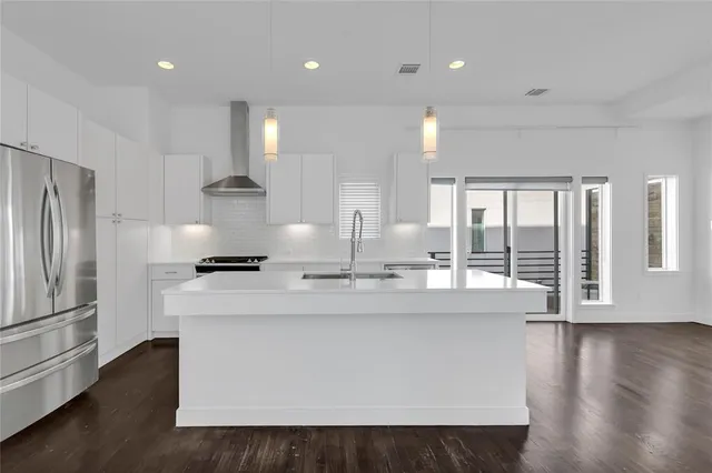 a large kitchen with stainless steel appliances a large counter top a refrigerator and a view of living room
