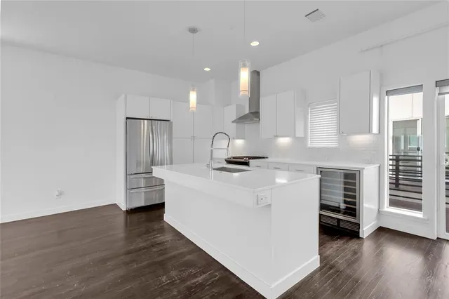 a kitchen with stainless steel appliances a sink and wooden floor