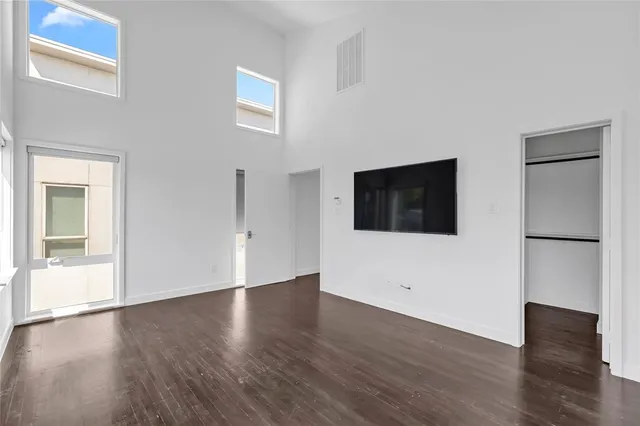 a view of an empty room with wooden floor and windows