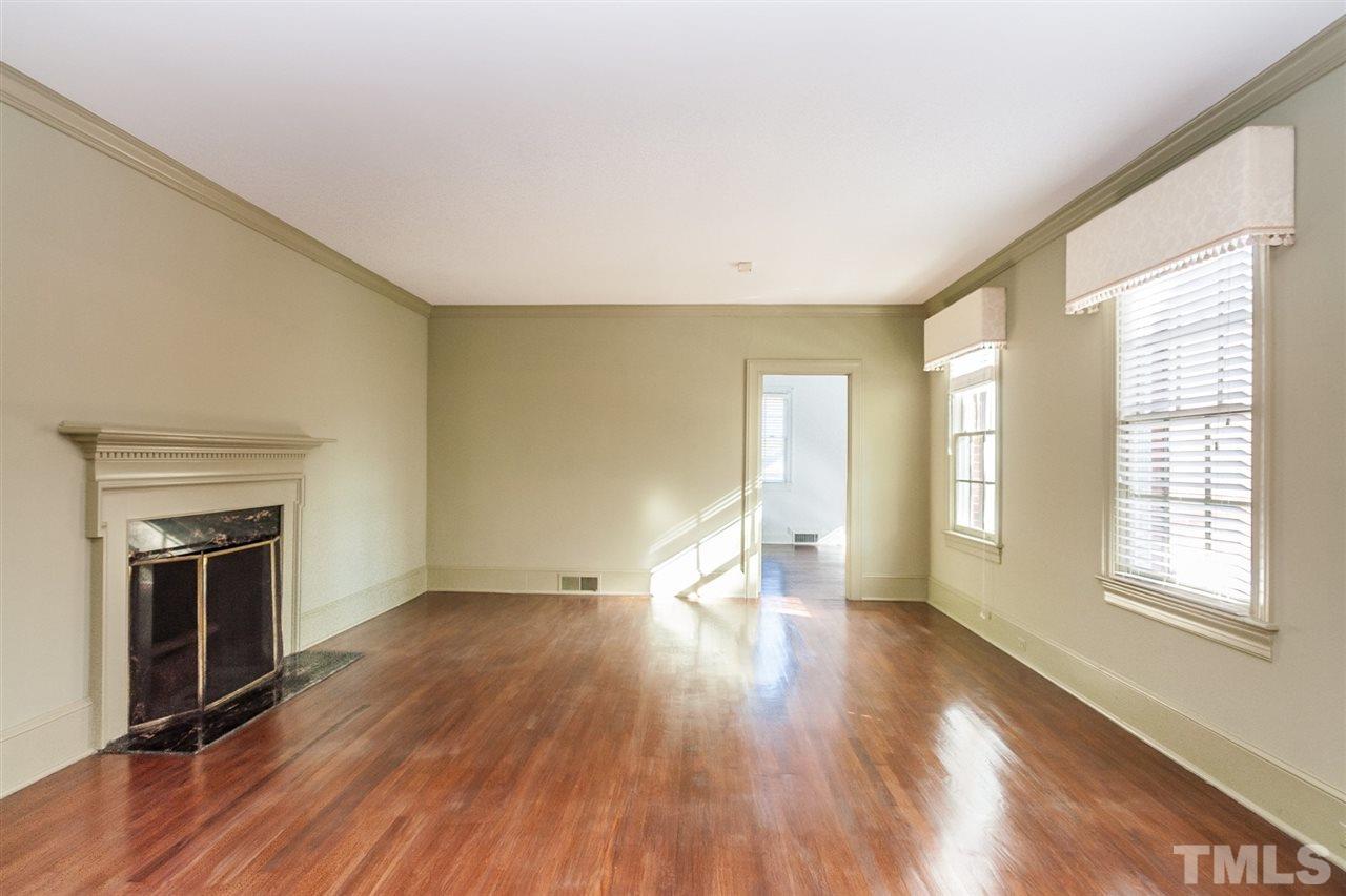 1707 Jarvis Street Raleigh, NC 27608 - Photo 5 of 25 an empty room with wooden floor fireplace and windows