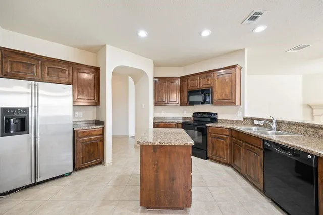 an empty room with chandelier fan and windows