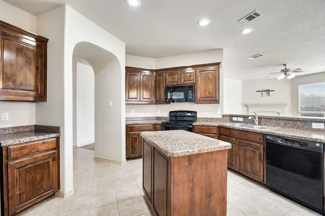 a large kitchen with stainless steel appliances granite countertop a stove a sink and a refrigerator
