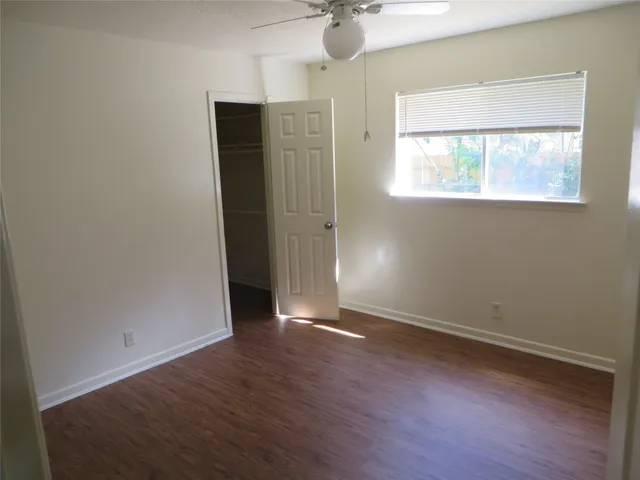 an empty room with wooden floor cabinet and windows