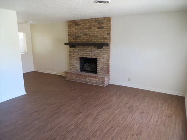 a view of empty room with wooden floor and fireplace