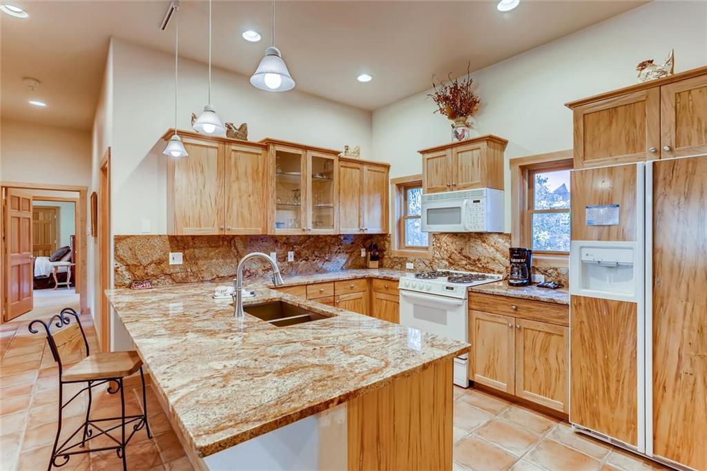 56 River Run Road, Unit 301 Keystone, CO 80435 - Photo 7 of 30 a kitchen with a stove a refrigerator and wooden cabinets