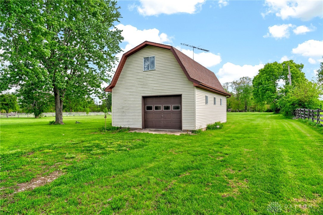1005 Free Road New Carlisle, OH 45344 - Photo 41 of 43 This charming outbuilding offers versatile space with a functional garage door and peaceful green surroundings.