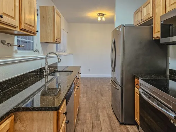 a kitchen with a refrigerator a sink and wooden floor