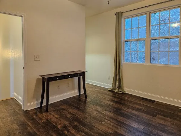 a view of an empty room with wooden floor and a window