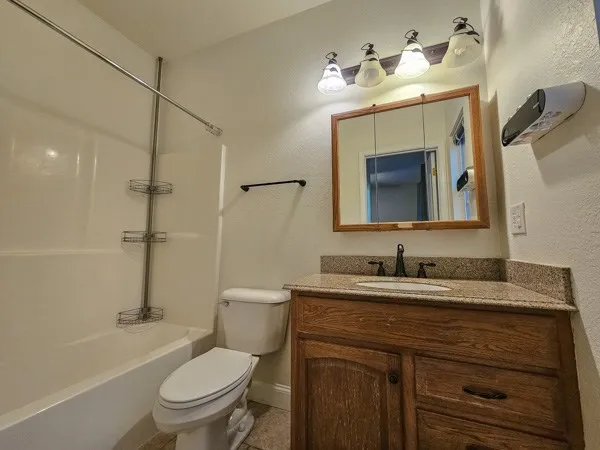 a bathroom with a granite countertop toilet sink and mirror