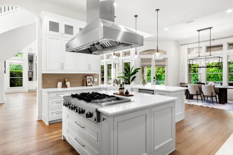 a kitchen with stainless steel appliances granite countertop a stove a sink a refrigerator and chairs
