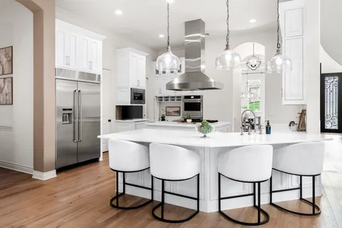 a kitchen with stainless steel appliances kitchen island granite countertop a refrigerator a stove a kitchen island with chairs and wooden floor