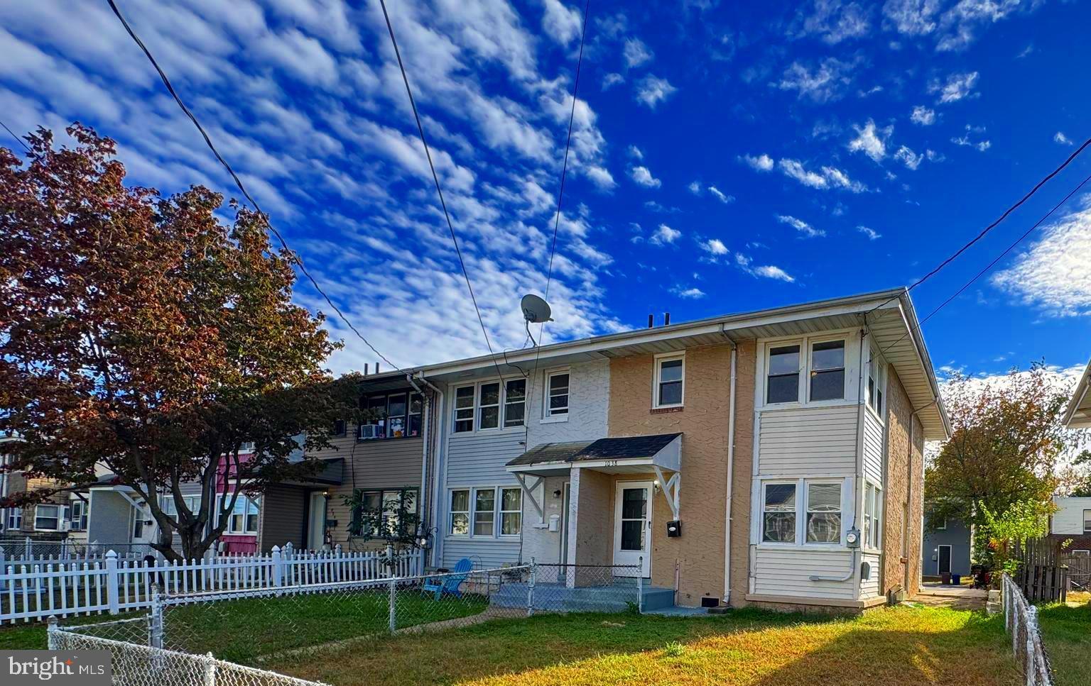 a view of a house with a big yard plants and large tree