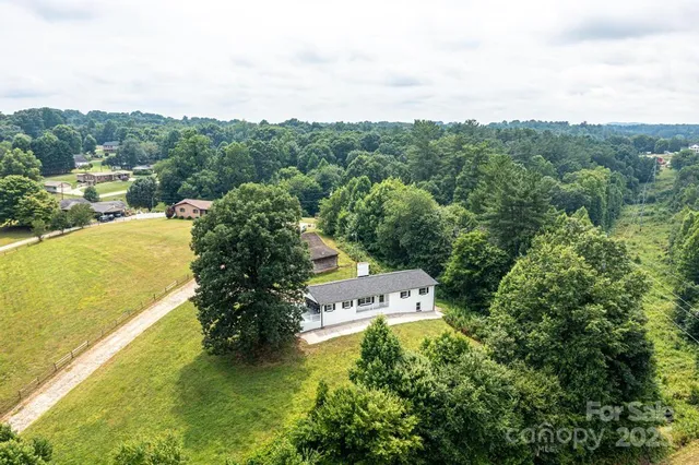an aerial view of residential houses with outdoor space and trees