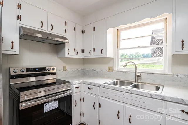 a kitchen with stainless steel appliances a sink a stove and cabinets