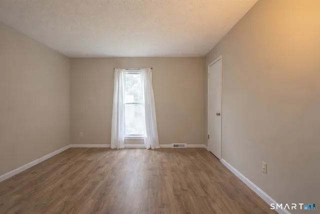 an empty room with wooden floor and window
