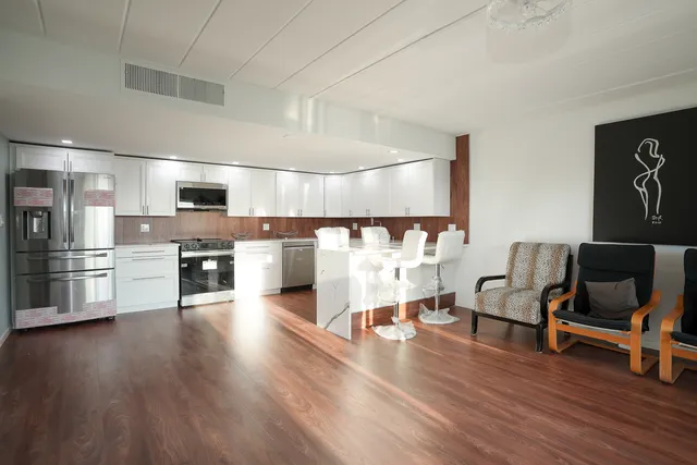 a view of kitchen with stainless steel appliances wooden floor and chair