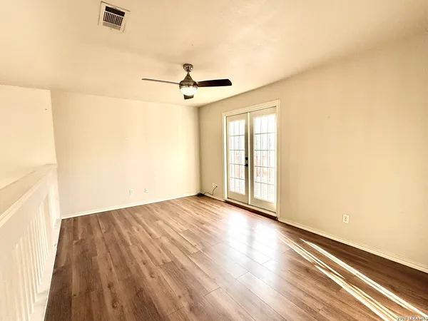 a view of empty room with wooden floor and fan