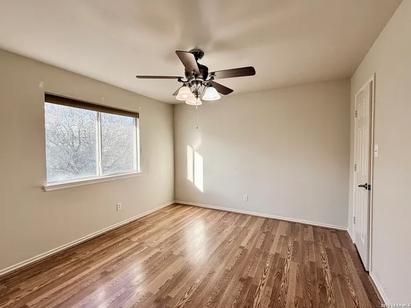 a view of an empty room with a window and a ceiling fan