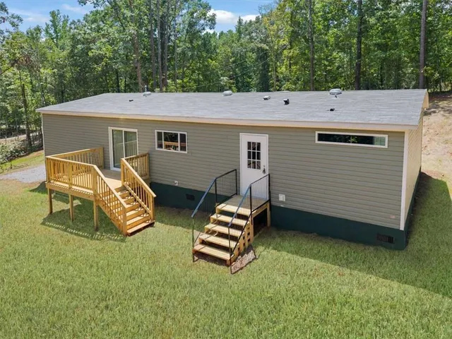 a backyard of a house with wooden deck and outdoor seating