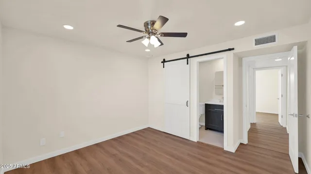 a view of empty room with wooden floor and ceiling fan