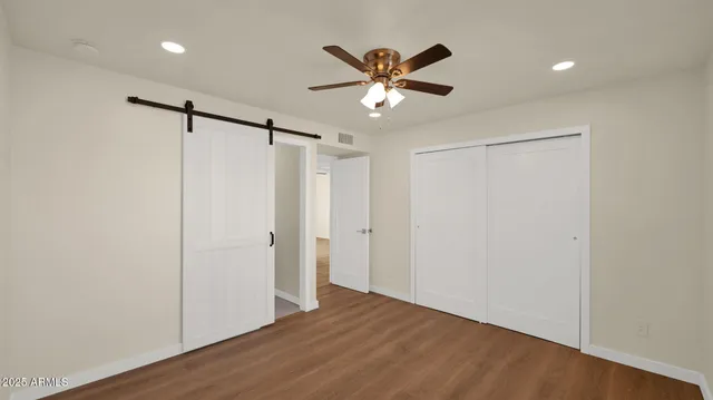 a view of empty room with wooden floor and fan