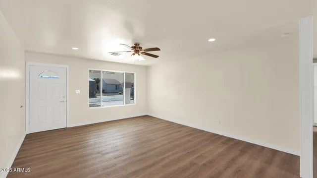 a view of an empty room with a window and wooden floor