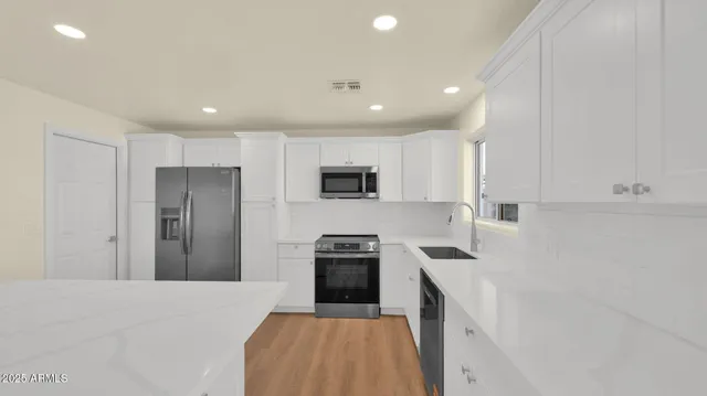 a kitchen with granite countertop white cabinets and stainless steel appliances