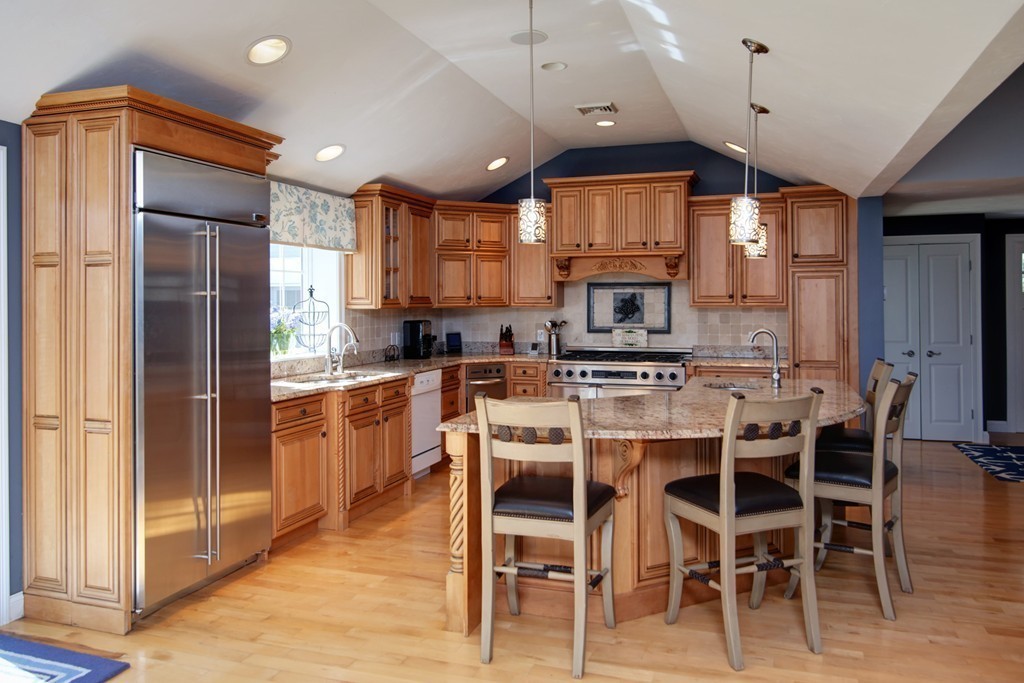 84 Troon Place Mashpee, MA 02649 - Photo 9 of 30 a kitchen with stainless steel appliances kitchen island granite countertop a refrigerator a stove top oven and a dining table with wooden floor