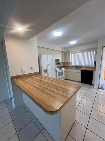 a room with kitchen island a sink a stove a counter space and cabinets