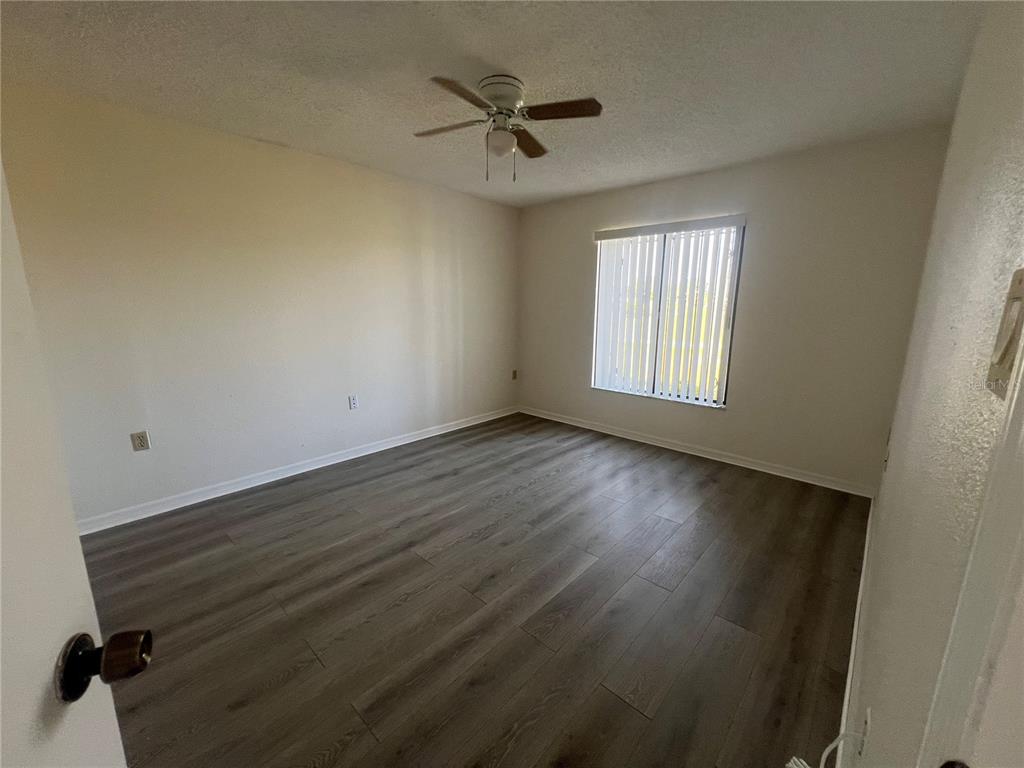 1330 Rio De Janeiro Avenue, Unit 5 Punta Gorda, FL 33983 - Photo 8 of 17 an empty room with wooden floor fan and windows