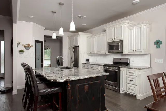 a kitchen with kitchen island granite countertop a table chairs microwave and cabinets