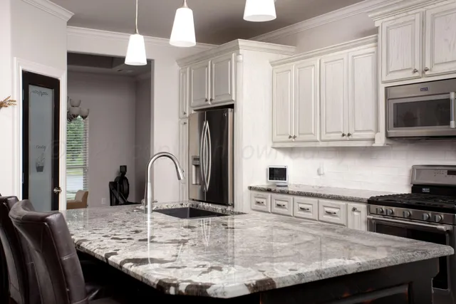 a kitchen with kitchen island granite countertop a stove a sink a refrigerator and cabinets
