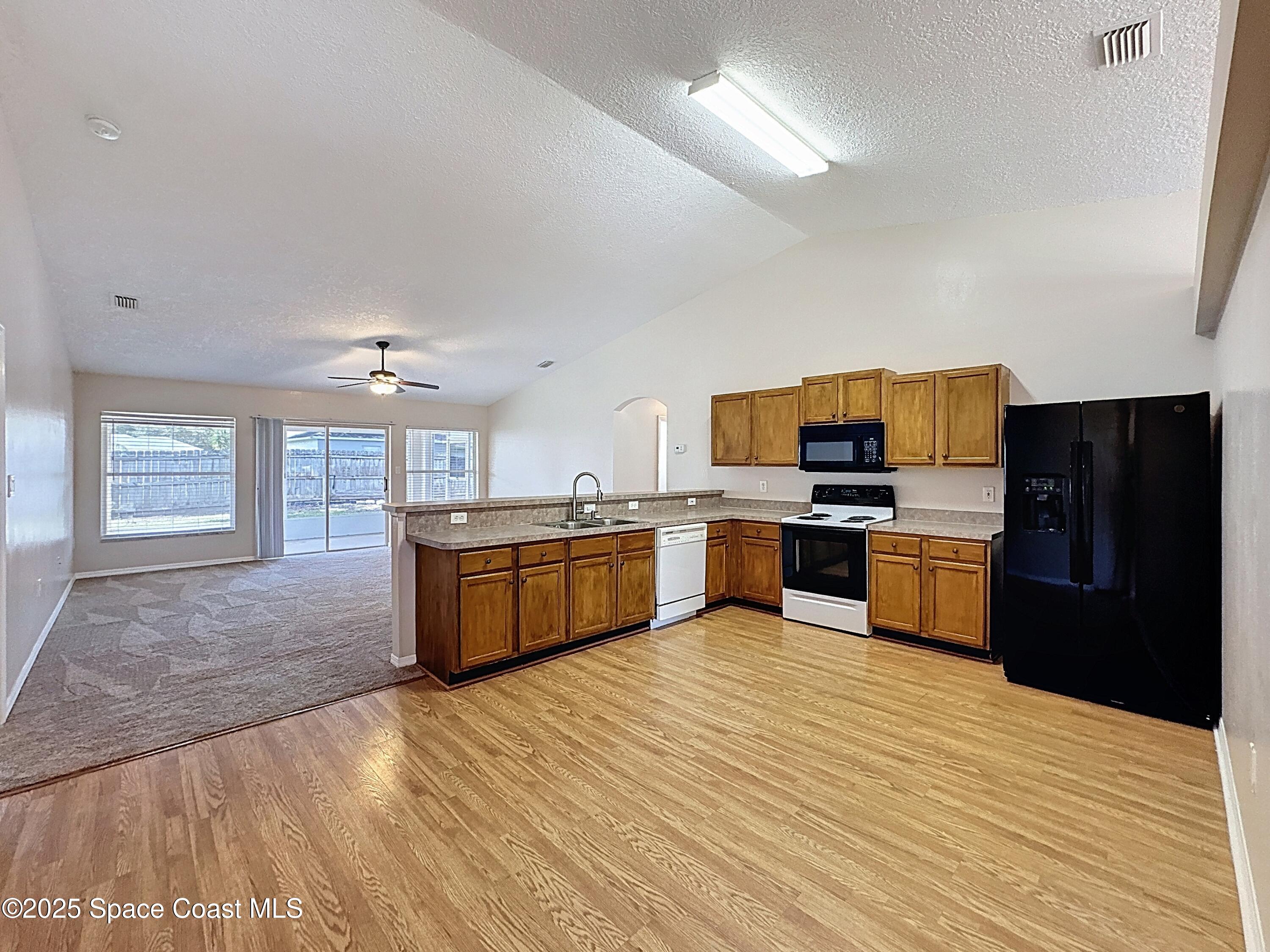 7370 Joshua Place Cocoa, FL 32927 - Photo 7 of 21 a large kitchen with stainless steel appliances wooden floors and wooden cabinets