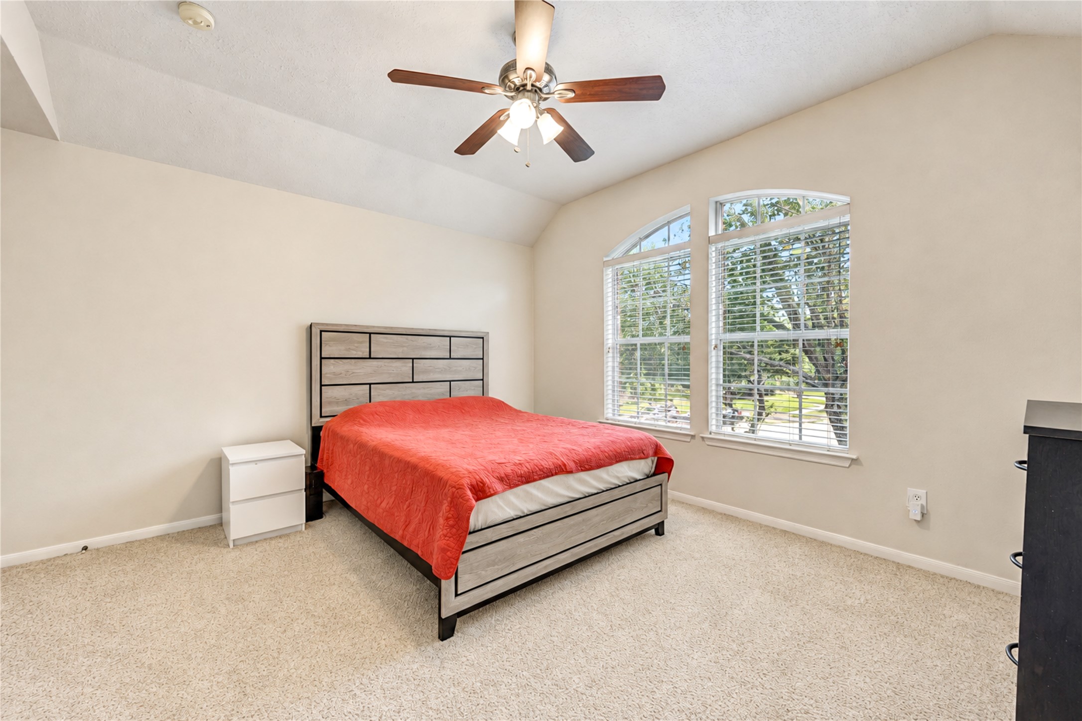 12806 Ridge Bank Lane Houston, TX 77041 - Photo 29 of 44 Bright and spacious bedroom featuring vaulted ceilings, a large arched window for natural light, and neutral carpeting, creating a cozy and inviting atmosphere.