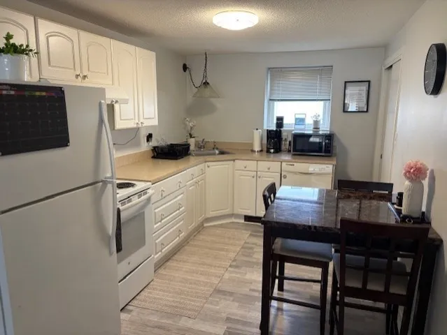 a kitchen with white cabinets and white appliances
