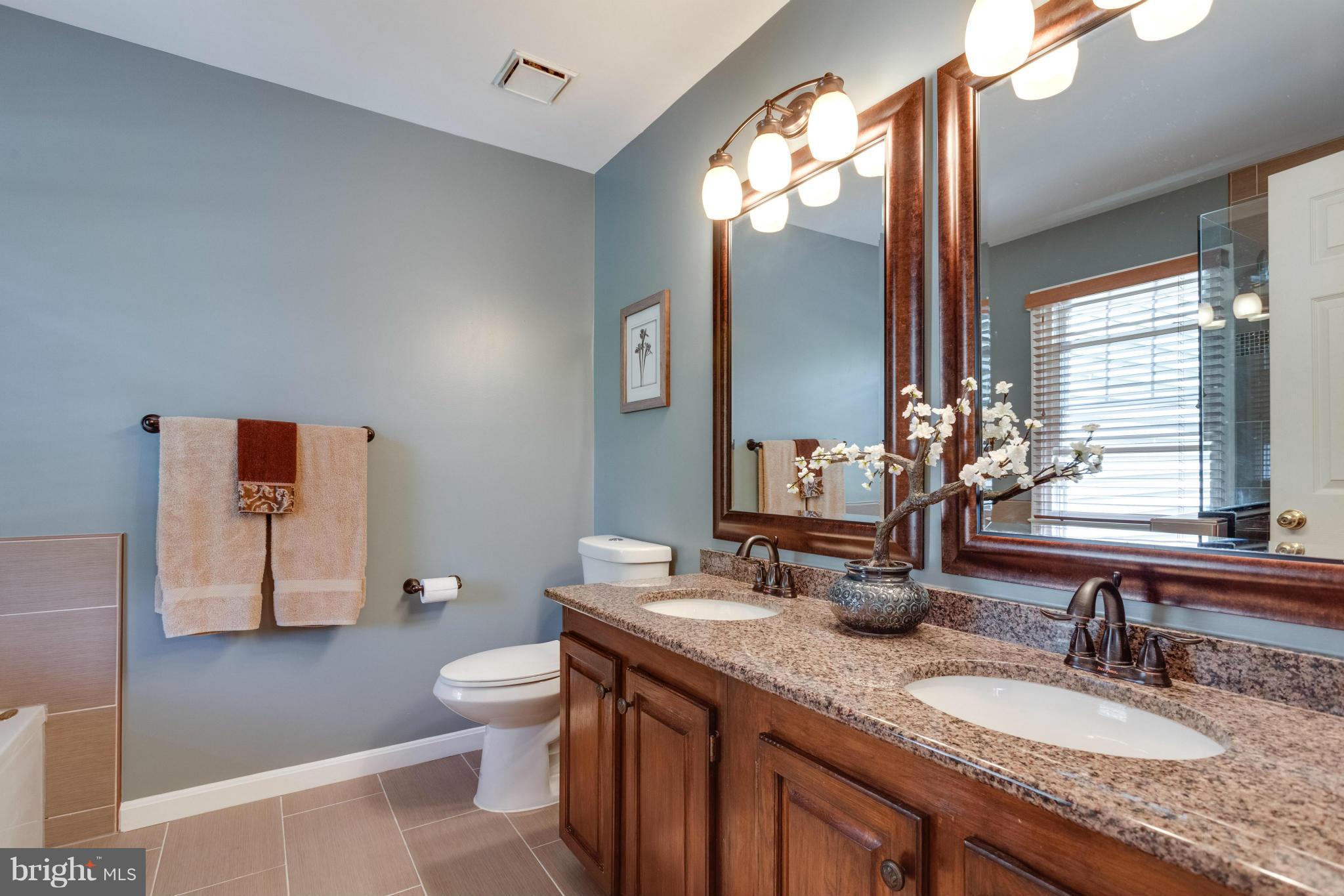 1215 Weatherstone Court Reston, VA 20194 - Photo 15 of 30 a bathroom with a granite countertop sink a toilet and a large mirror