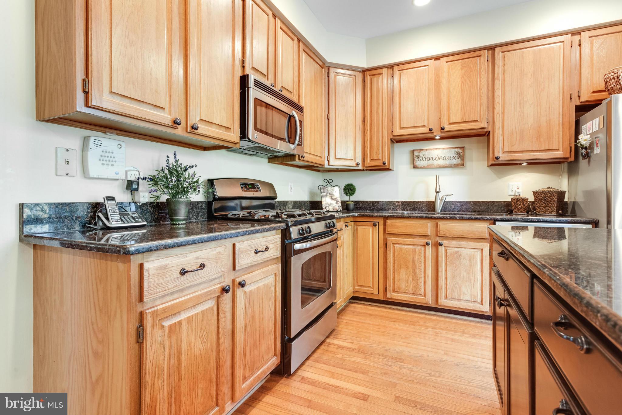 1215 Weatherstone Court Reston, VA 20194 - Photo 8 of 30 a kitchen with stainless steel appliances granite countertop white cabinets sink and a granite counter top
