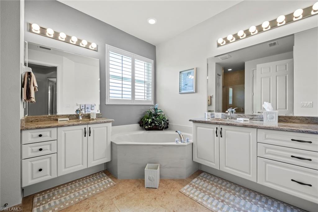 9006 Whitfield Drive Estero, FL 33928 - Photo 19 of 43 a bathroom with a granite countertop double vanity sink a mirror a vanity and a bathtub