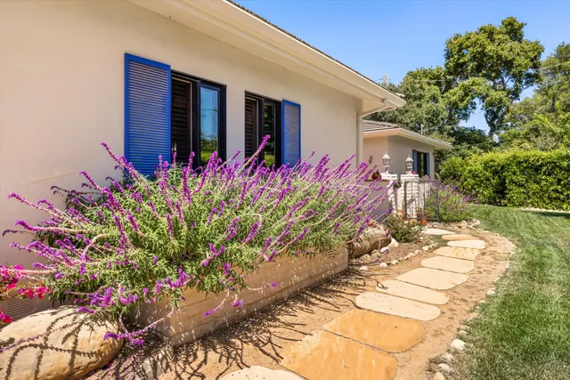 a front view of a house with a yard and potted plants