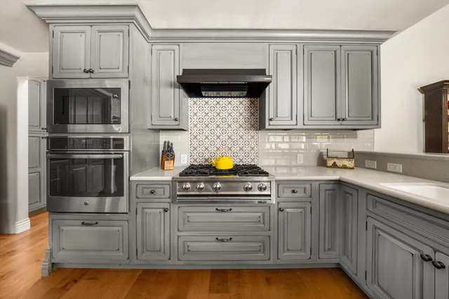 a kitchen with stainless steel appliances granite countertop a stove a sink and a microwave