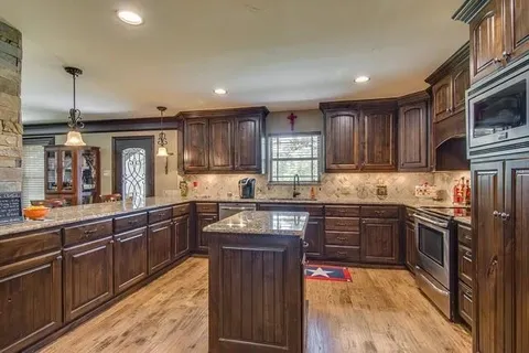 a kitchen with stainless steel appliances granite countertop wooden cabinets sink and stove