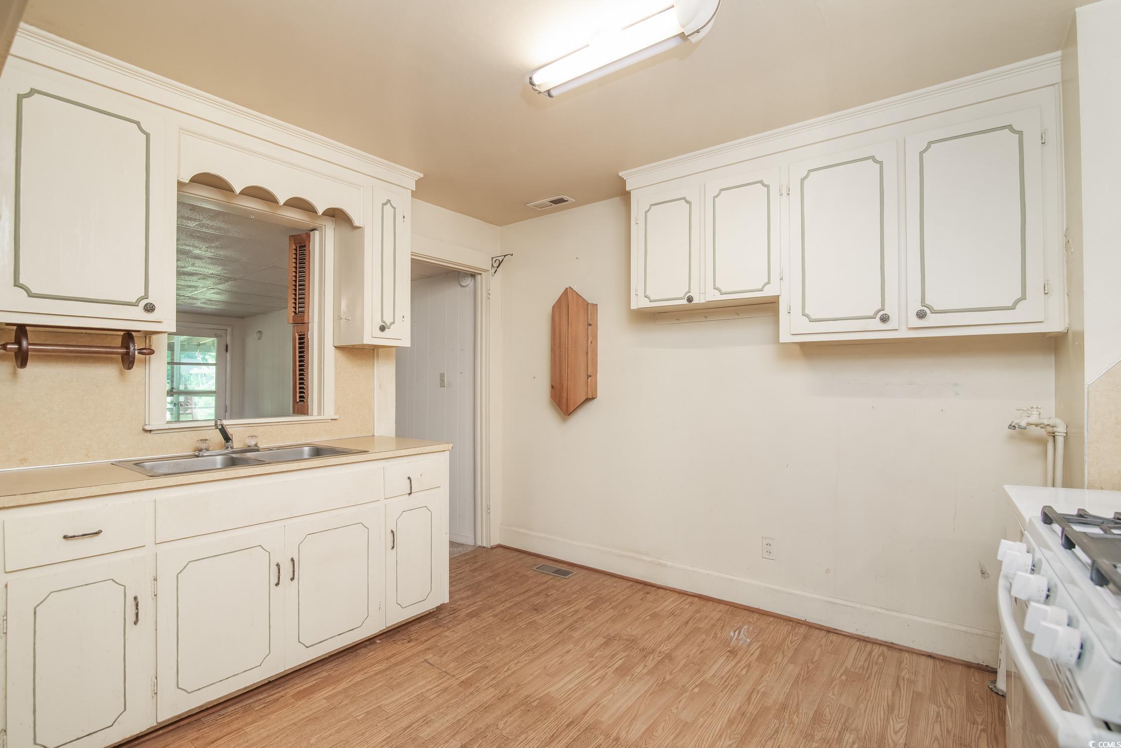 704 North Congdon Street Georgetown, SC 29440 - Photo 10 of 35 Kitchen featuring white gas range oven, a sink, light wood-style floors, and white cabinetry