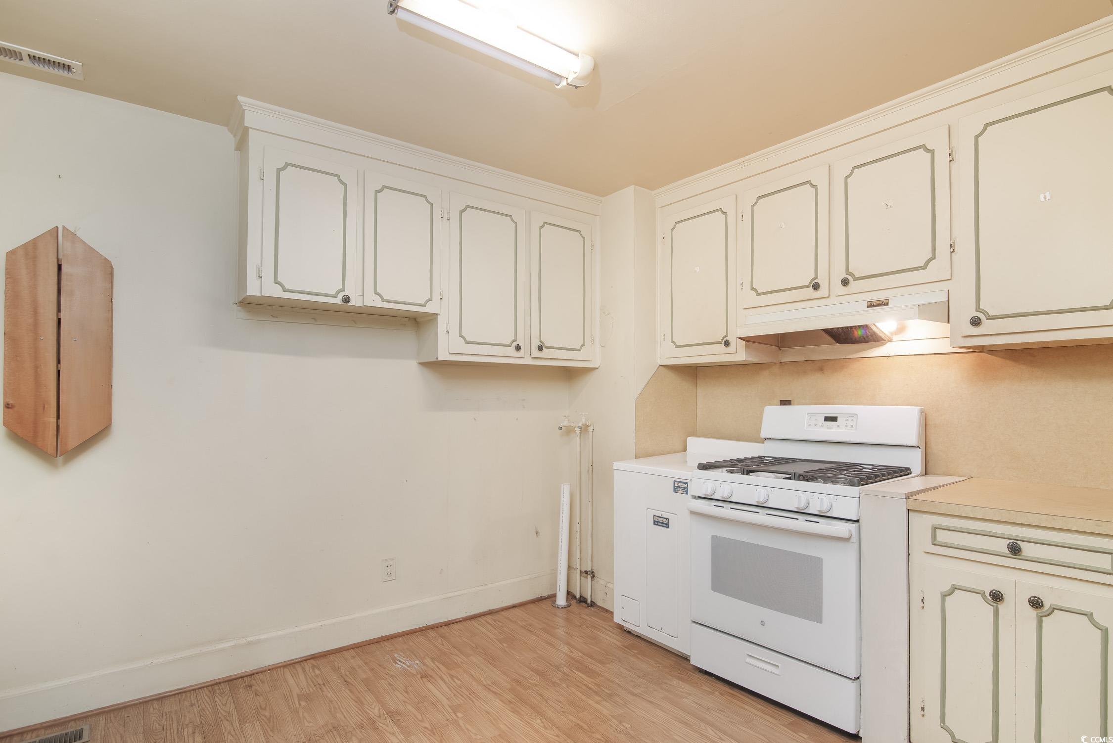 704 North Congdon Street Georgetown, SC 29440 - Photo 11 of 35 Kitchen with white range with gas cooktop, under cabinet range hood, light wood-style flooring, light countertops, and baseboards