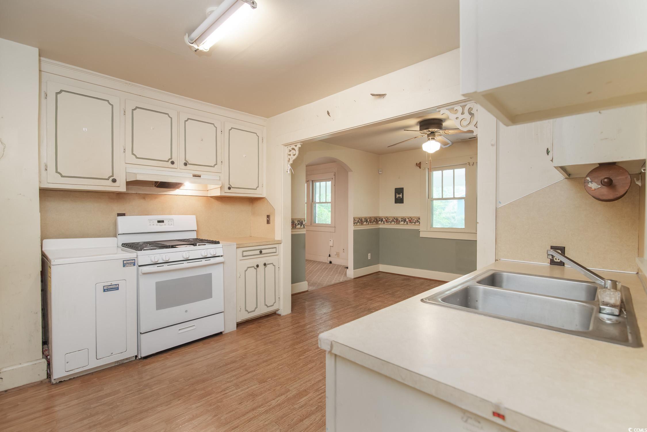 704 North Congdon Street Georgetown, SC 29440 - Photo 12 of 35 Kitchen with white range with gas stovetop, a sink, under cabinet range hood, light wood-type flooring, and light countertops