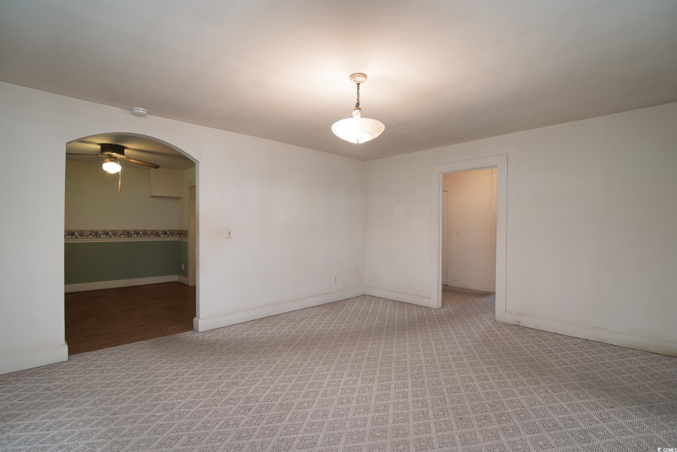 704 North Congdon Street Georgetown, SC 29440 - Photo 17 of 35 Empty room with a ceiling fan, light colored carpet, arched walkways, and baseboards