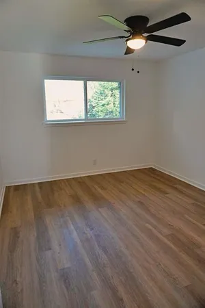 a view of an empty room with wooden floor and a window