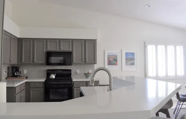 a kitchen with granite countertop a stove a sink and a microwave