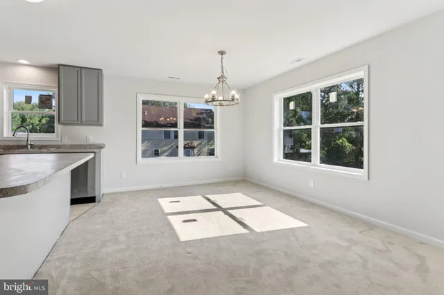 an empty room with windows and open kitchen