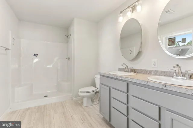 a bathroom with a double vanity sink mirror and toilet