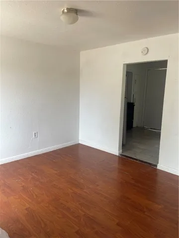 a view of an empty room with wooden floor and closet